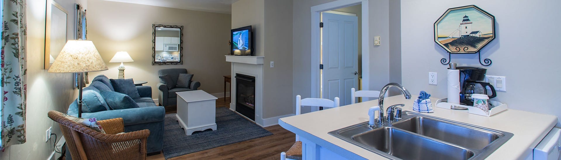 Hotel suite with kitchenette, living room with couch, two chairs, gas fireplace and TV