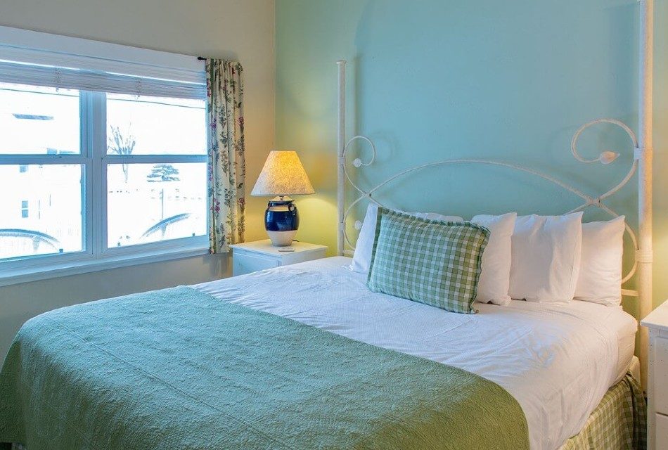 Bright bedroom with queen bed, side tables with lamps and large window with floral curtains