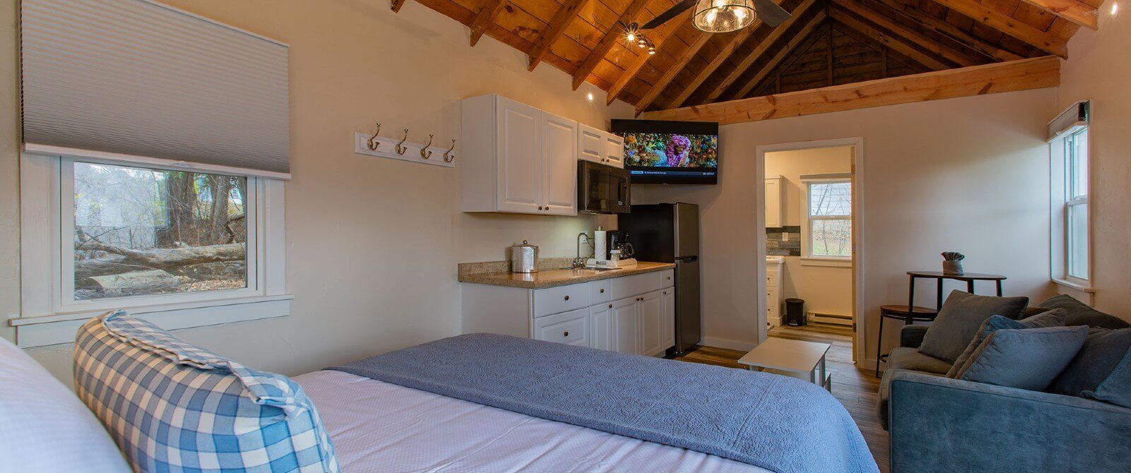 Interior of a cottage with open floor plan, queen bed, living room, kitchen and tall a-frame ceiling