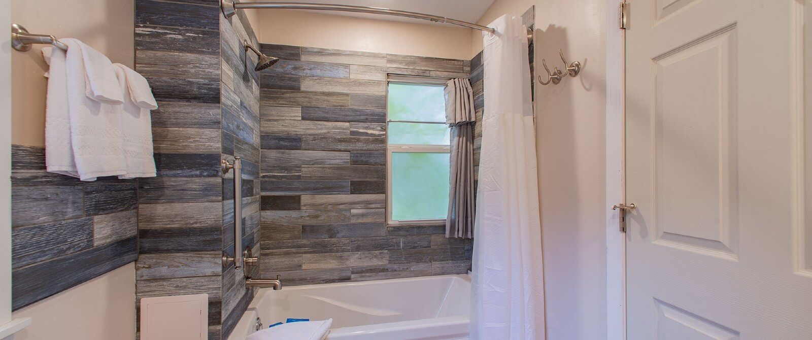 Bathroom with tiled stand up shower, white shower curtain and small window