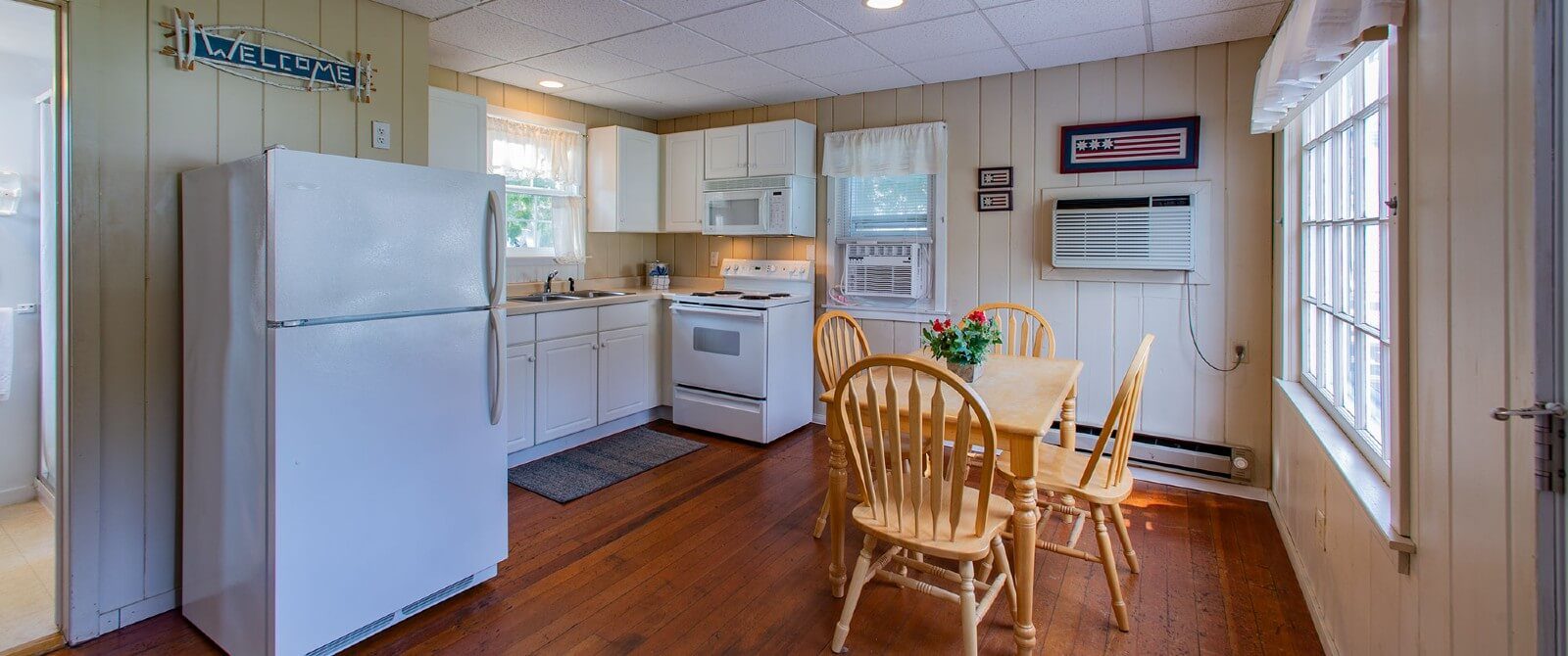 Interior of a cottage with small kitchen, table for with four chairs, and hardwood floors