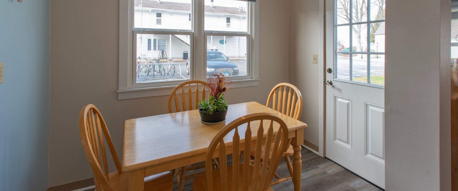 Small breakfast nook with wood table with four chairs and large picture window next to a door