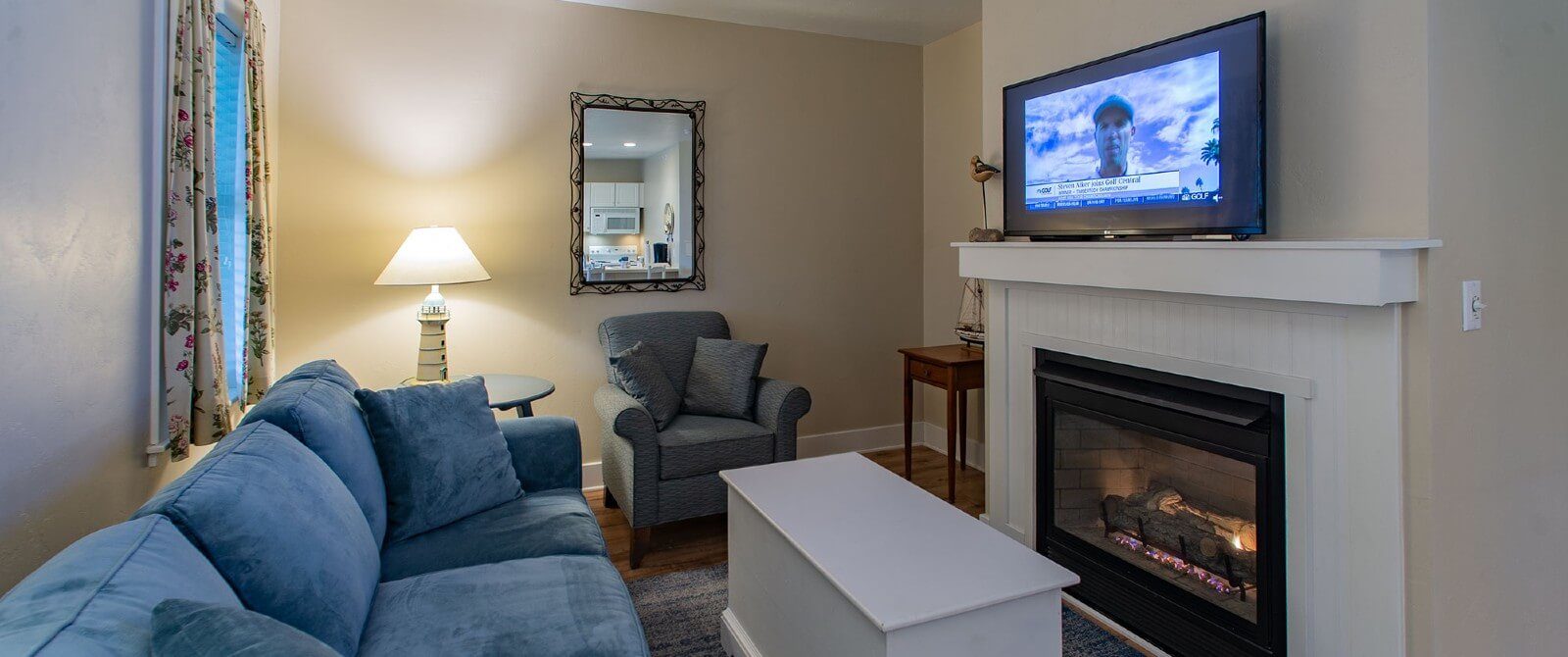 Living room with plush couch and chair, coffee table in front of gas fireplace wth TV on mantle