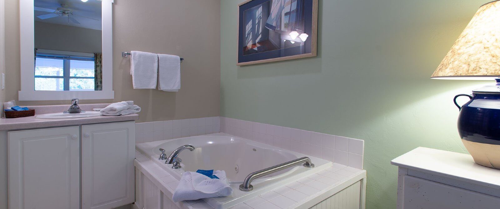 Bathroom with large soaker jacuzzi tub, vanity, white framed mirror and white towels on a rack