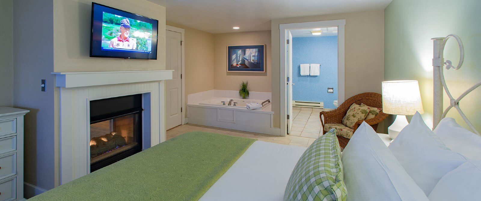 Spacious bedroom with king bed, TV above gas fireplace and corner jacuzzi tub