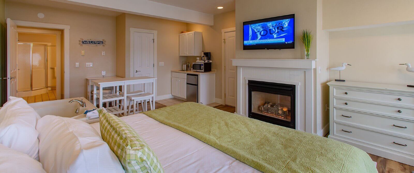 Bedroom with king bed, soaker tub, bistro table with stools, kitchenette and gas fireplace with flat screen TV