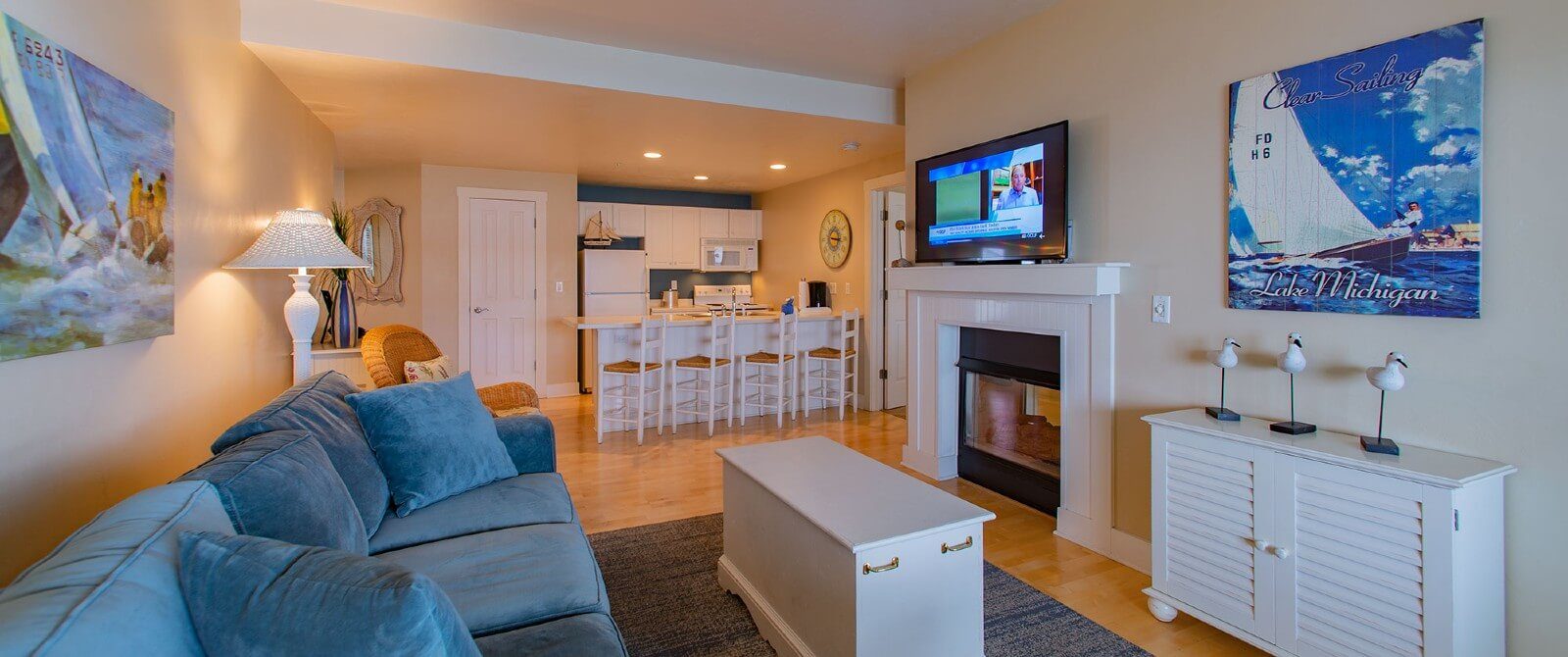Large suite with kitchen, island with four stools, couch in front of a gas fireplace with TV on the mantle