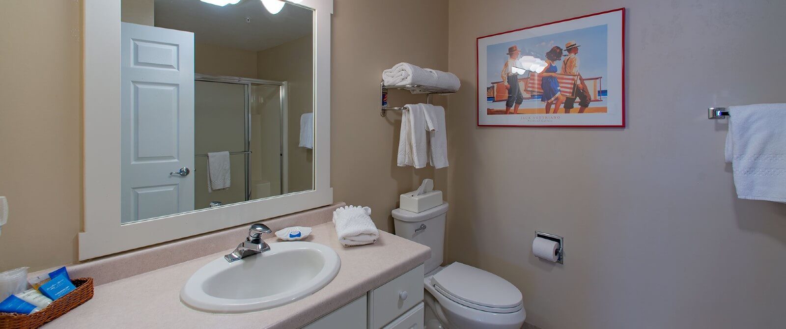 Bathroom with single sink vanity, white framed mirror, toilet and white towels