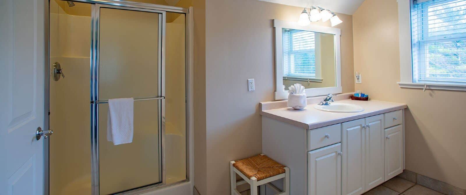 Bathroom with single sink vanity, white framed mirror and stand up shower with slider glass door