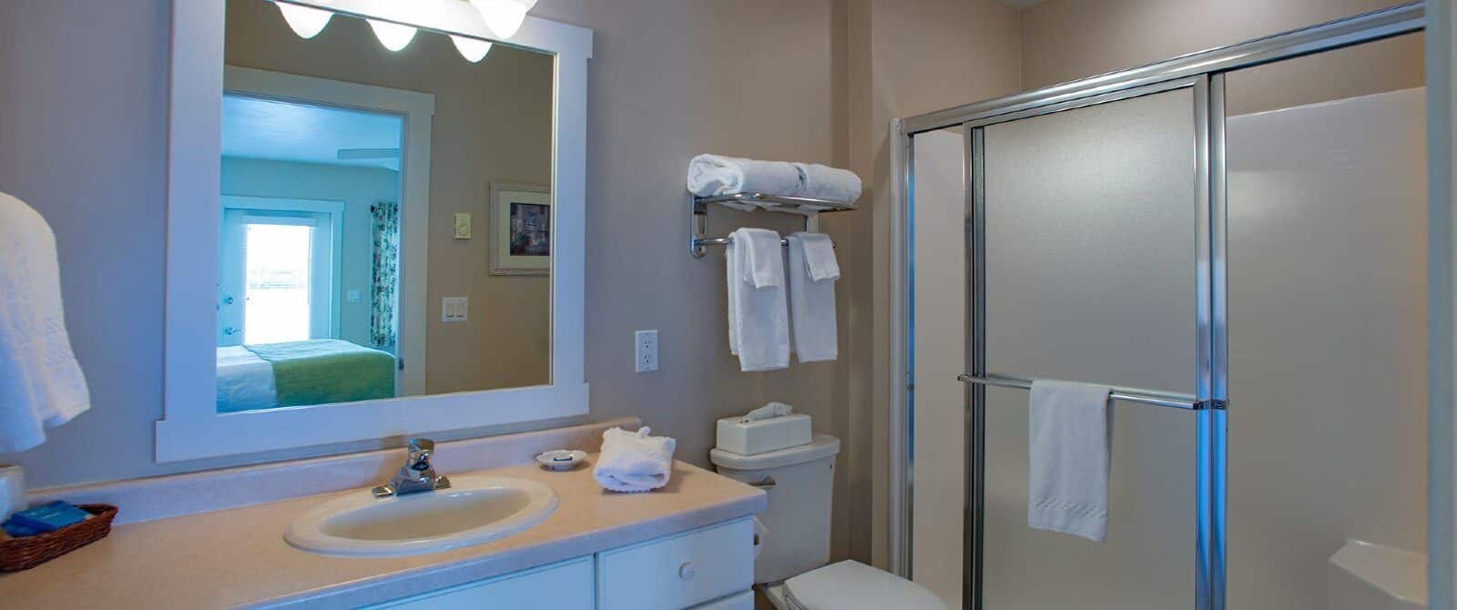 Bathroom with single sink vanity, white framed mirror, stand up shower with slider door