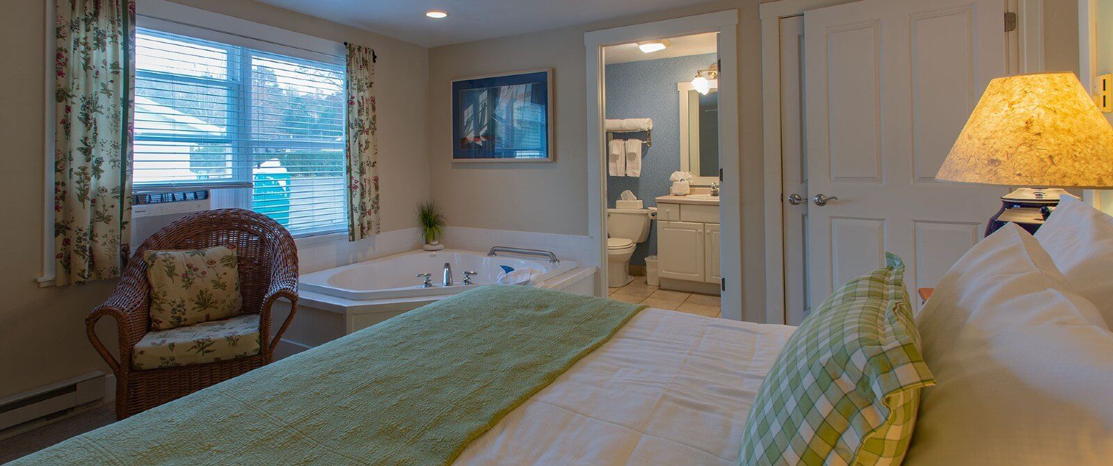 Bedroom with queen bed, corner jacuzzi tub and doorway open to a bathroom
