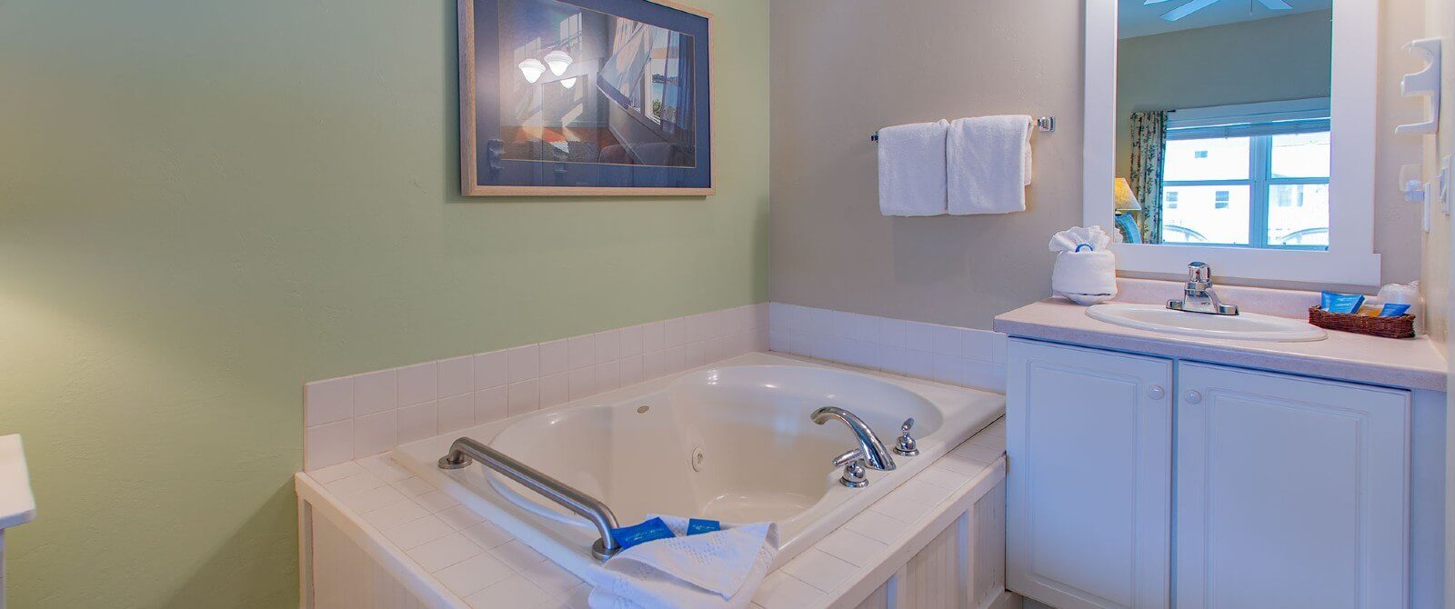 Large soaker tub next to single sink vanity with framed mirror