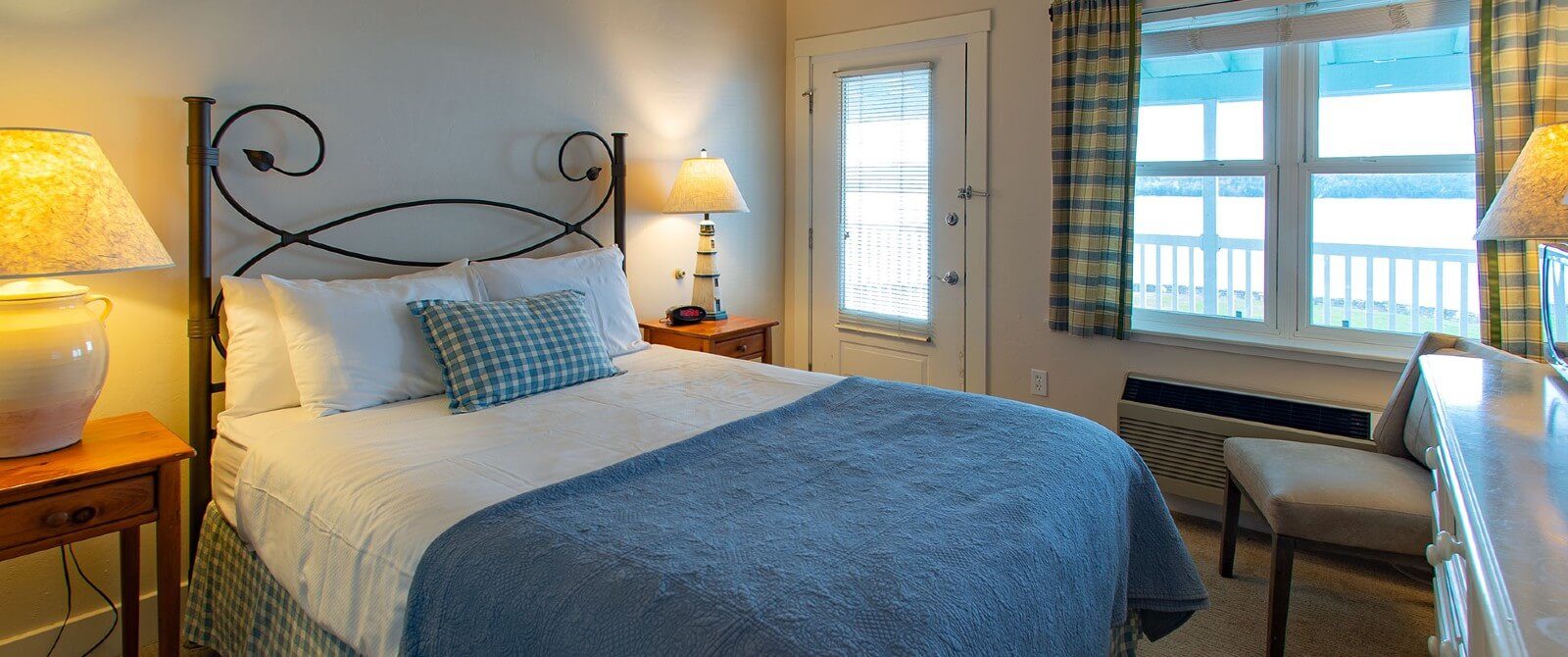 Cozy bedroom with queen bed, side tables with lamps and large window overlooking the water