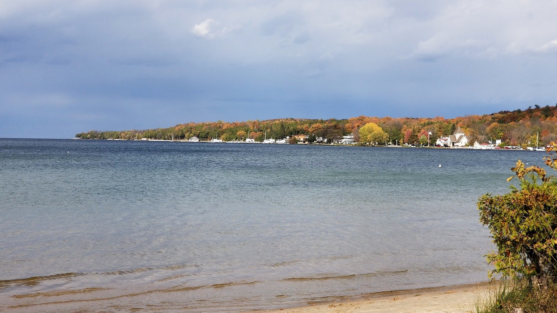 An expansive bay of a lake with the shoreline dotted with several homes and buildings