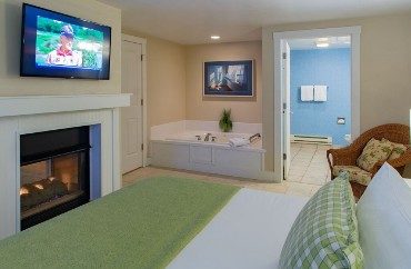 Bedroom with king bed, fireplace with flat screen TV, jacuzzi tub and doorway into a bathroom