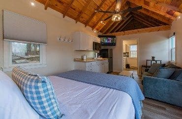 Interior of a cottage with open floor plan, queen bed, living room kitchen and tall a-frame ceiling